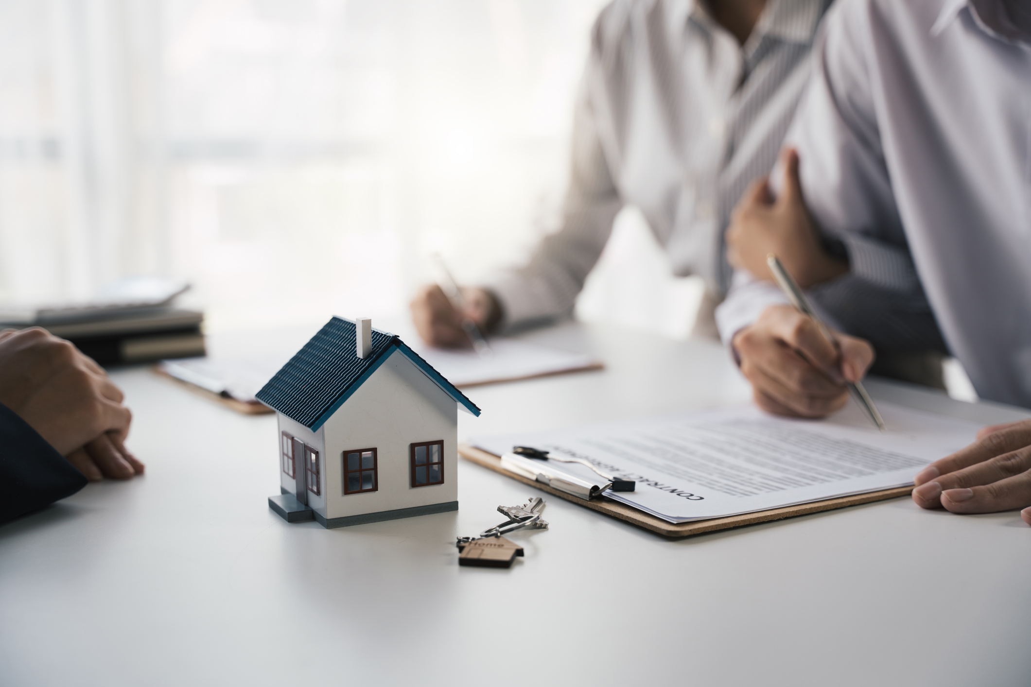 A small model house resting on top of signed real estate documents, symbolizing the financial planning involved in Arizona retirement tax strategies.