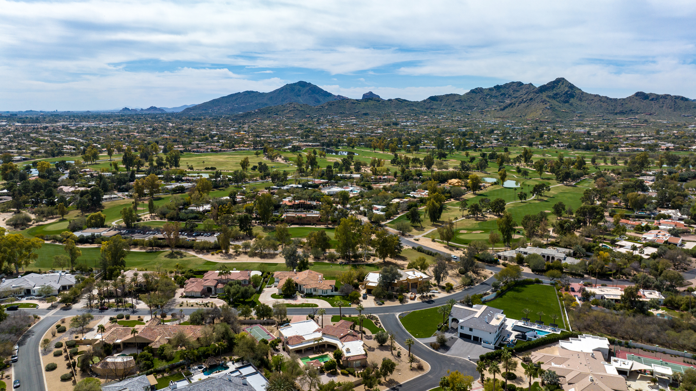 Aerial photograph of a North Scottsdale neighborhood featuring luxury homes with private pools adjacent to the McDowell Sonoran Preserve hiking trails.